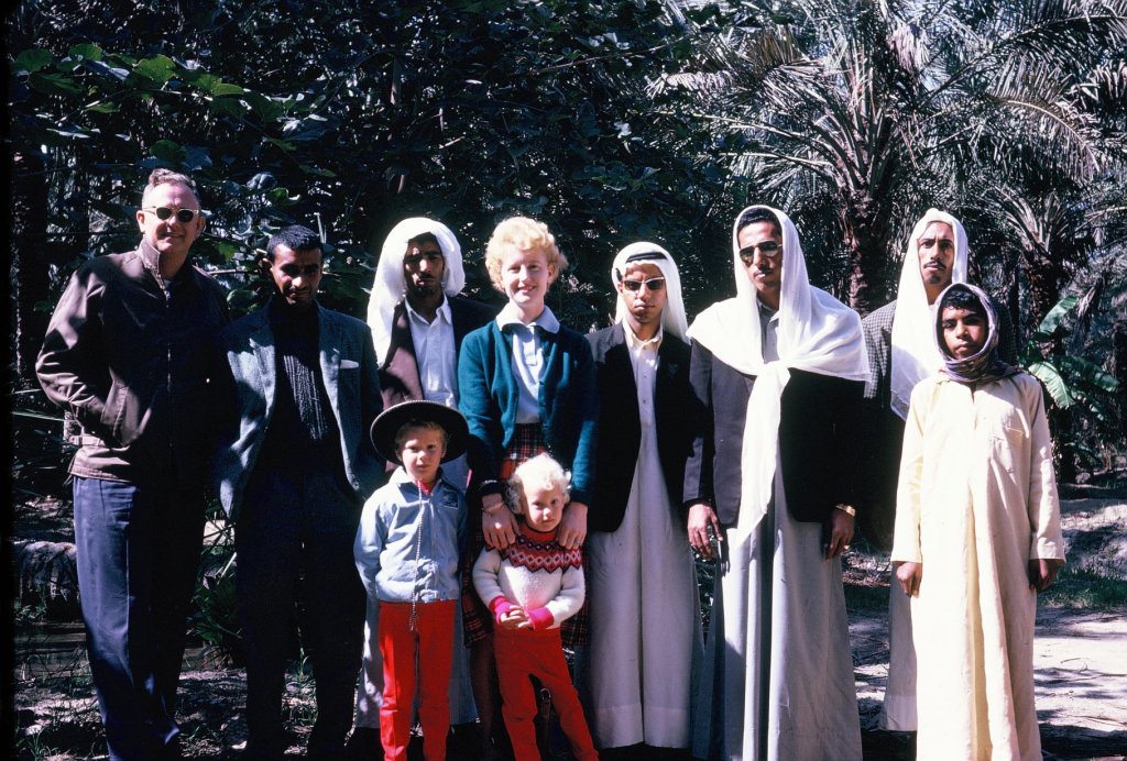 The author of Travel The Four Corners is a Third Culture Kid who grew up outside the country of her nationality and that of her parents. Even though she was born an American citizen, the U.S. was a culture shock when she returned in her teenage years. This photo shows her as a little girl with her family and their gardener, Ali during a visit to his village in Saudi Arabia.