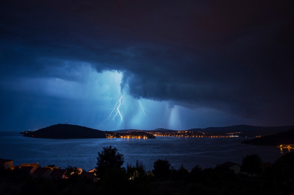 Storm clouds and bad weather over Adriatic Sea in Croatia. Lightning flashes over the village Rogoznica in Dalmatian coastline.